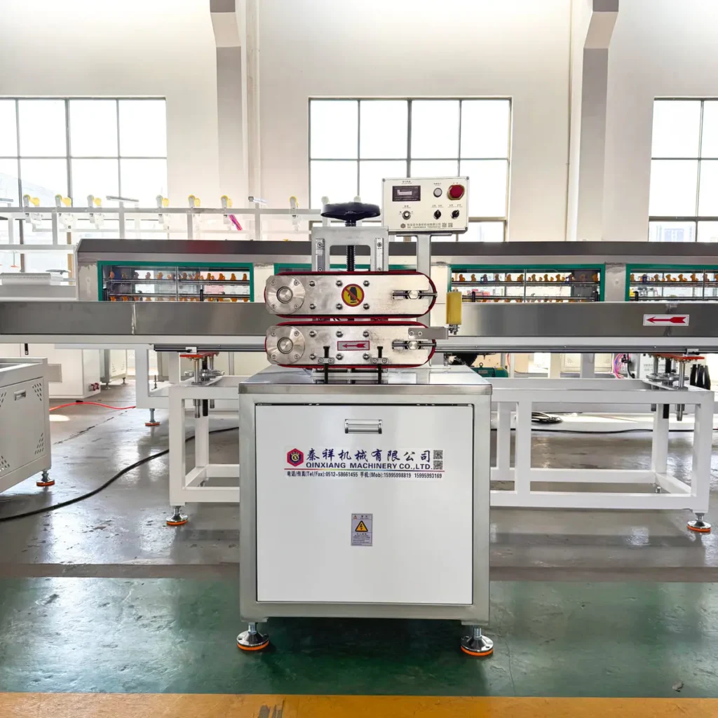 A belt haul-off machine with control panel stands in a brightly lit factory workshop with windows and concrete flooring