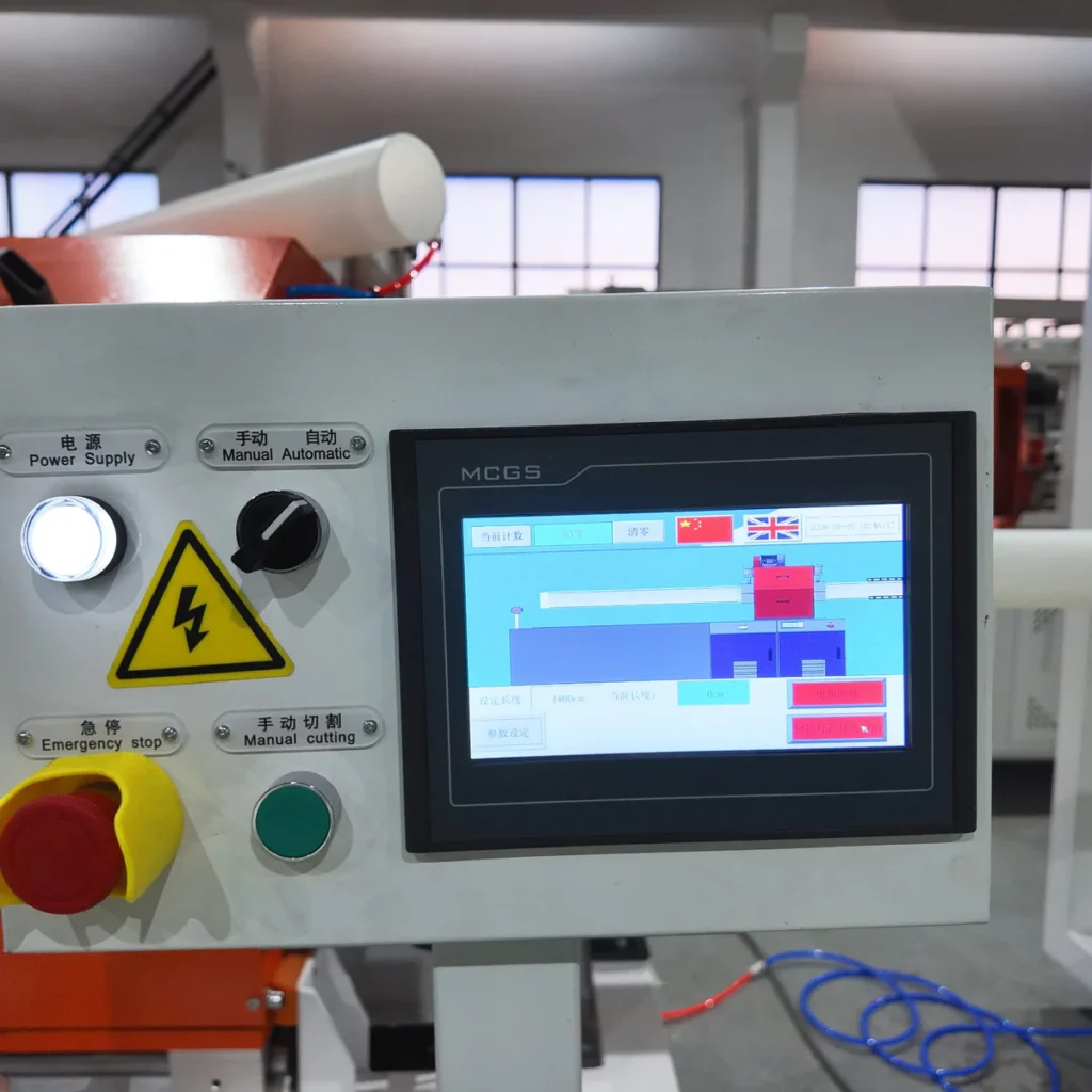 Closeup of a no-chip pipe cutting machine touch screen with control buttons and emergency stop in a factory setting