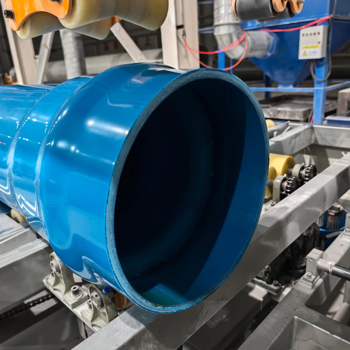 Rigid PVC pipe running out of the die head on a PVC extrusion line