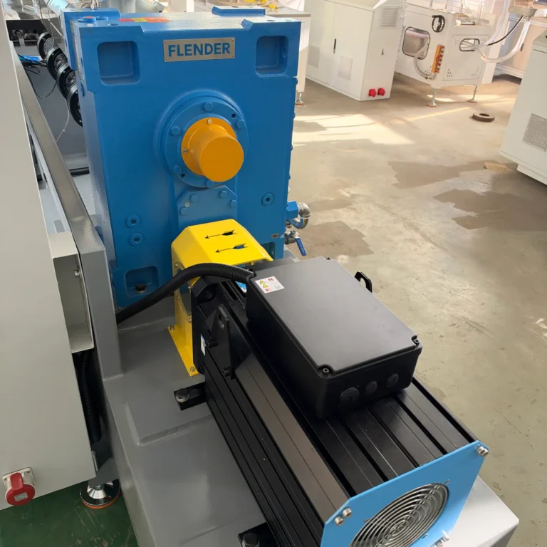 Closeup view of a blue gearbox and black motor assembly mounted on industrial equipment in a factory workshop