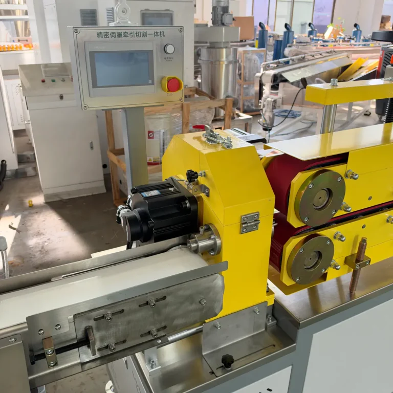 Yellow haul-off and cutting unit with control panel installed in a factory among other extrusion equipment