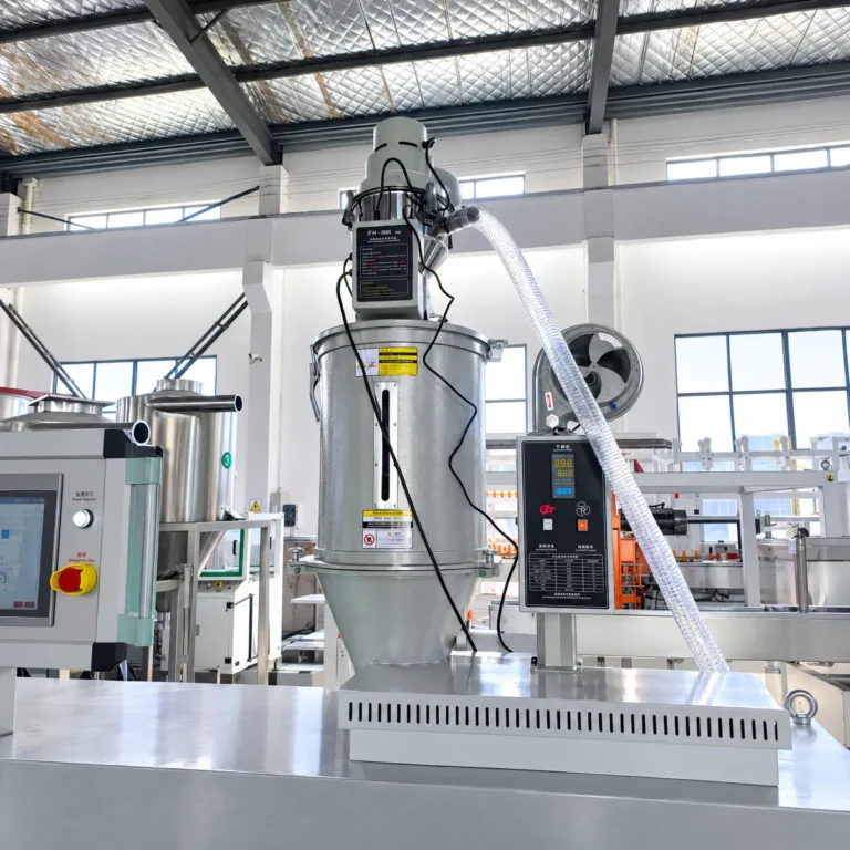 Metal hopper with vacuum loader and control panel in a factory setting, part of an insulated tumbler straw extrusion line