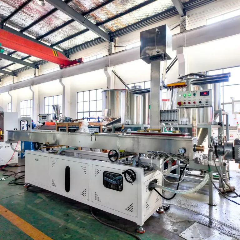 A plastic extrusion machine with a stainless steel hopper and control panel installed in a bright factory workshop