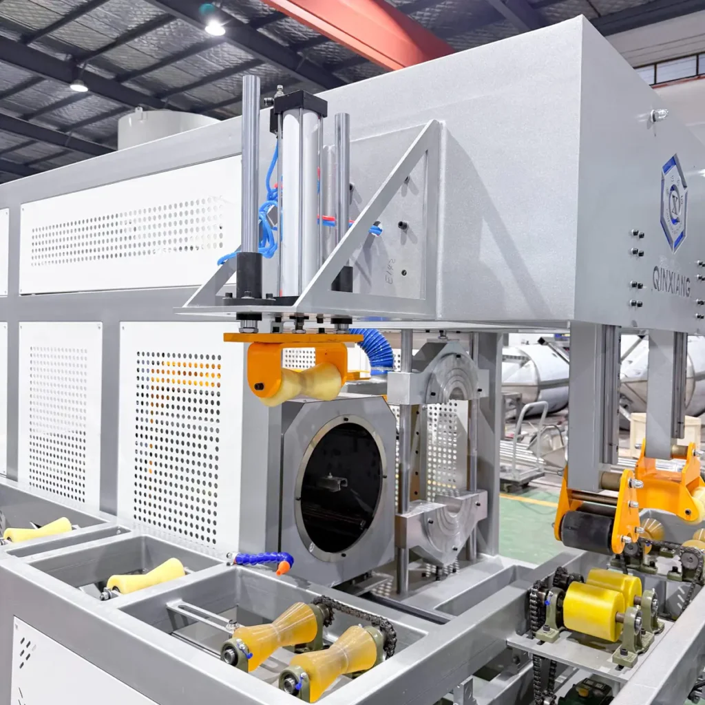 Closeup of a pipe socket forming machine with rollers and cutting unit in a factory environment