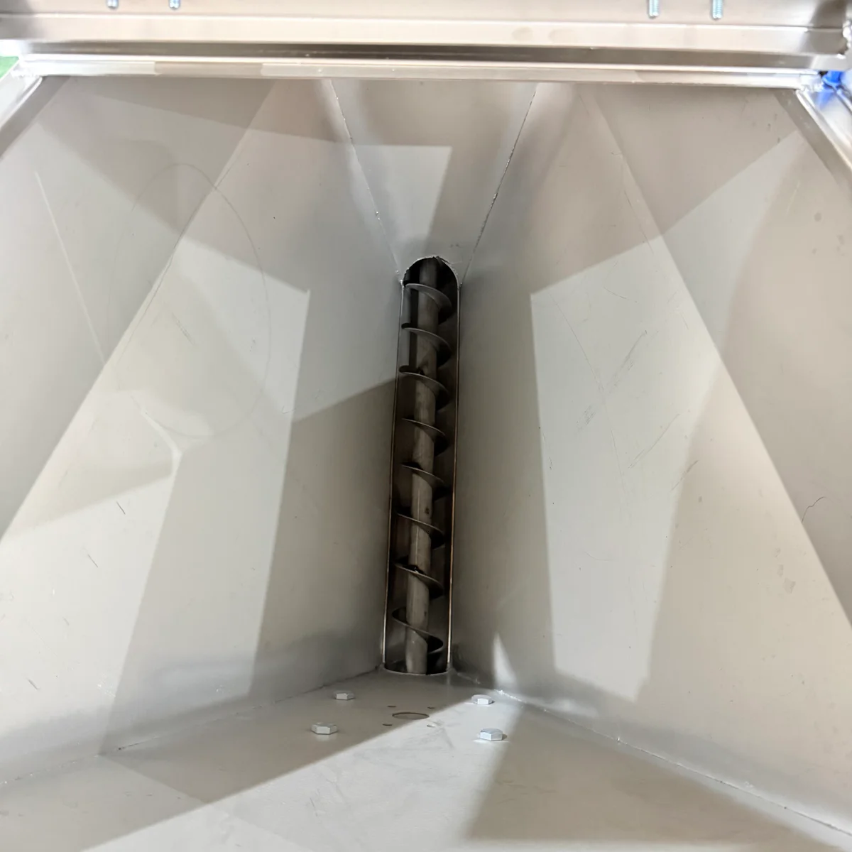 Irregular regrind flakes interlocking above the feeder screw inlet