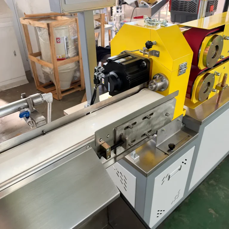 Yellow haul-off and cutter unit processing a flat white plastic profile in a factory environment