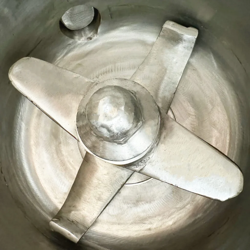 Closeup view of a metal powder hot mixer blade inside a cylindrical vessel