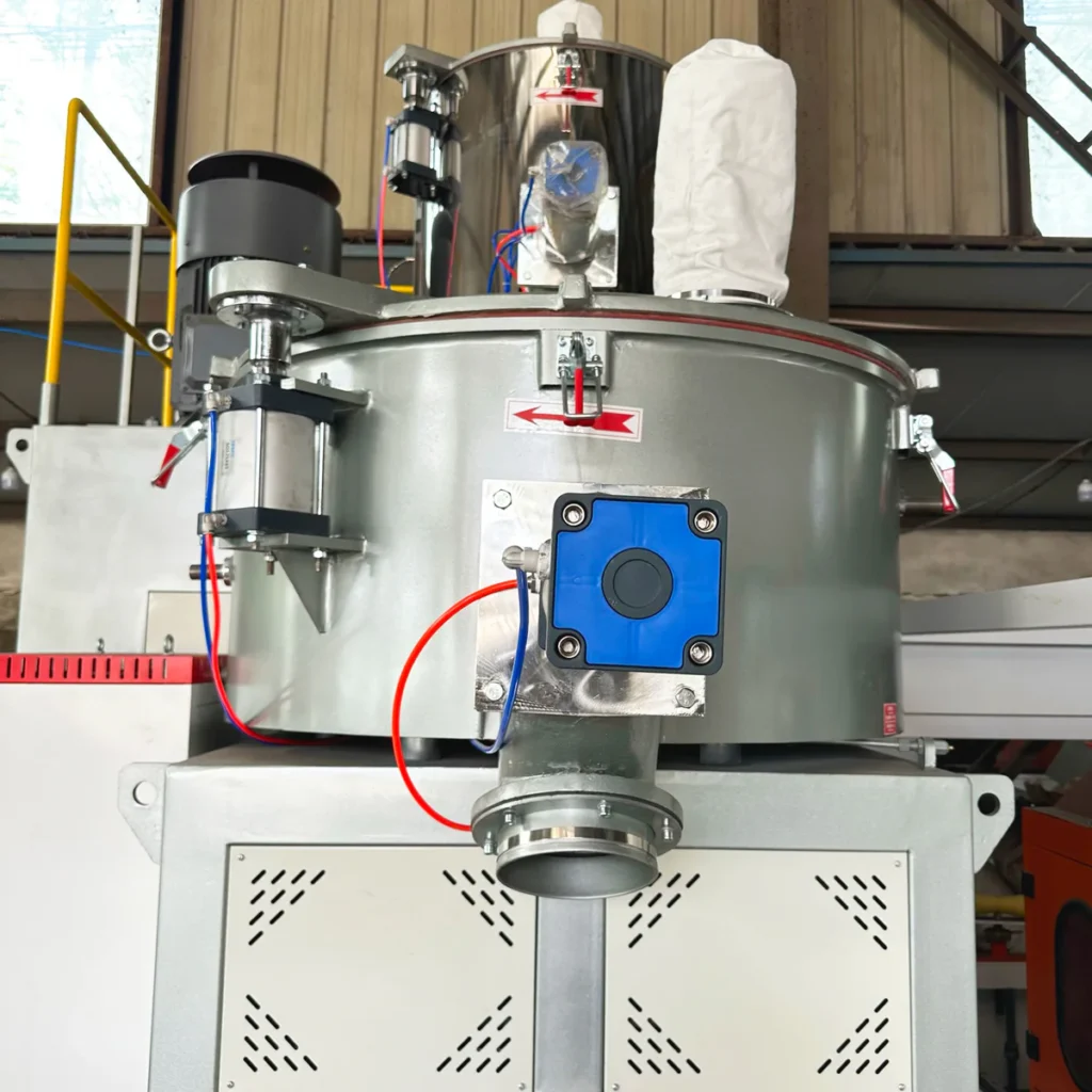 Closeup of an industrial PVC high speed mixing unit with pneumatic valves and control box in a factory setting