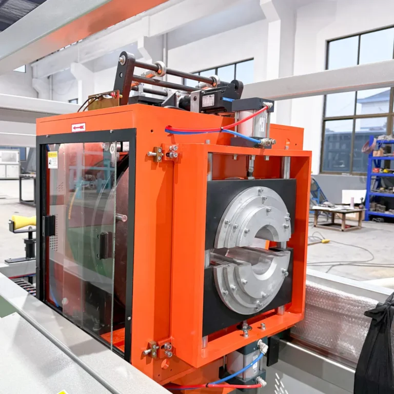 Closeup of an orange pipe cutting or belling unit with circular tooling inside a factory workshop
