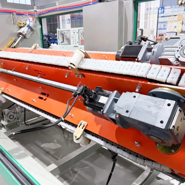 Closeup view of a four claw haul off unit with motors and caterpillar belts inside a factory setting
