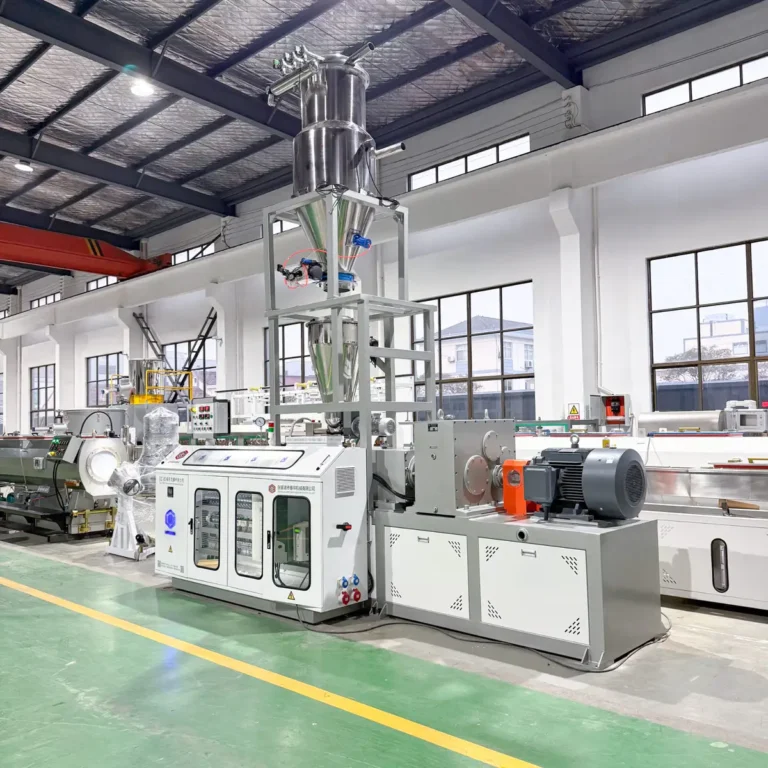 Plastic extrusion line with feeder and downstream units installed on a factory floor with large windows and overhead crane
