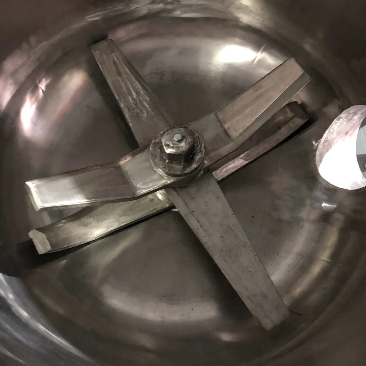 Technician checking blade fastening and shaft alignment inside a high-speed mixer
