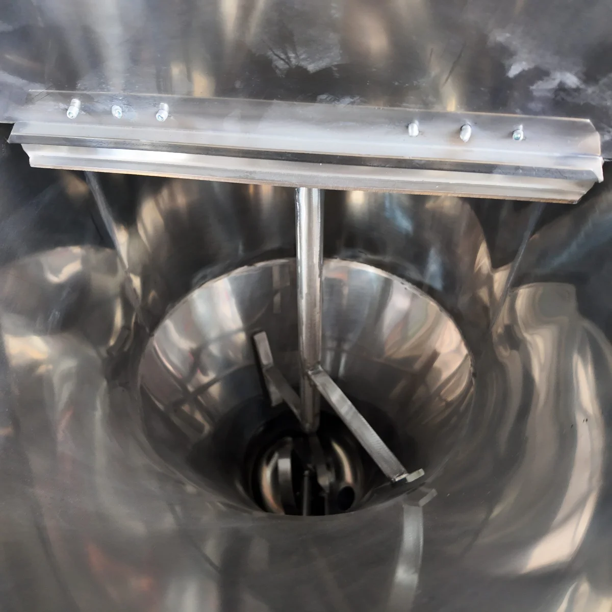 Irregular plastic regrind flakes of mixed particle size in a feeding hopper