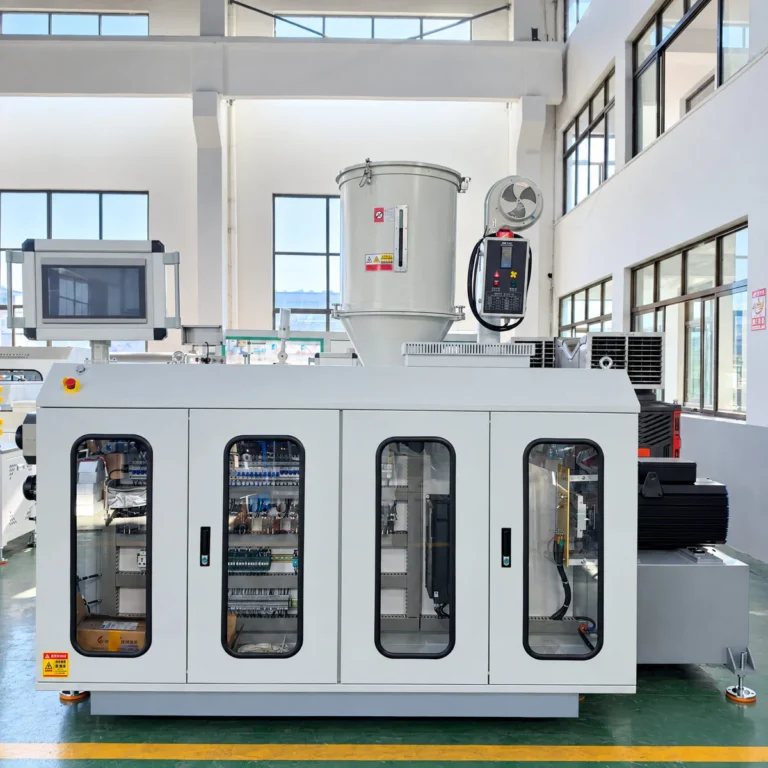 A white plastic extrusion machine with control cabinet and hopper installed in a factory workshop with large windows