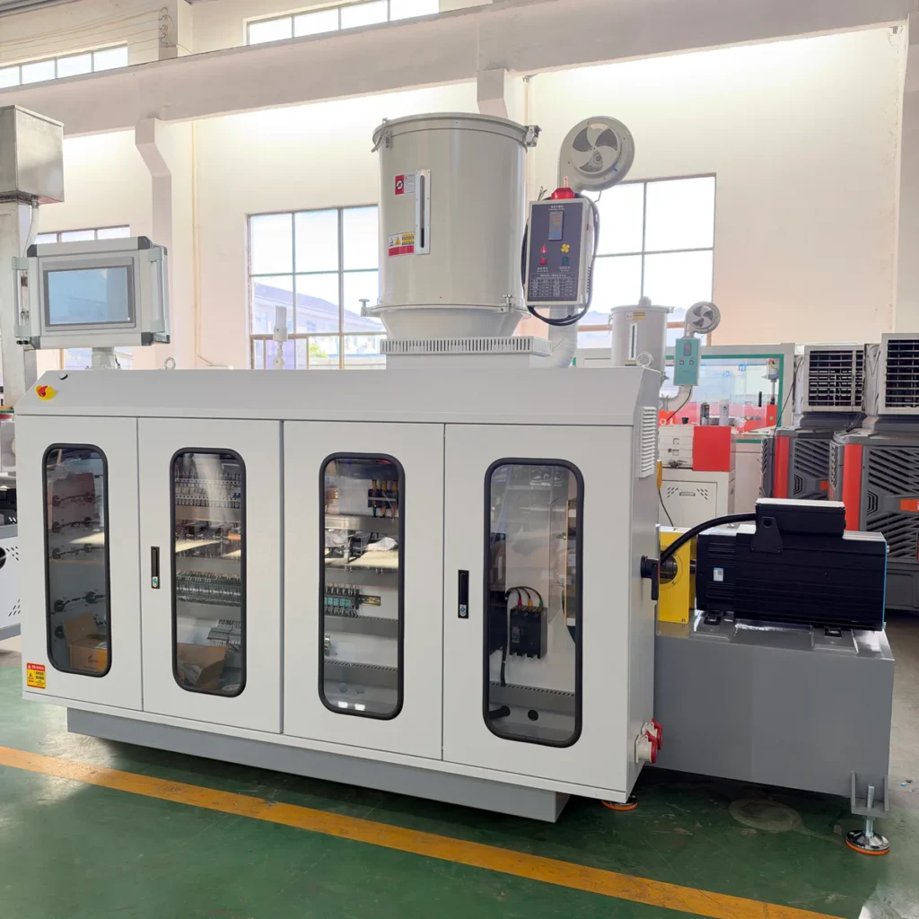 Large white electrical control cabinet with a hopper and motor, installed in a factory workshop with windows