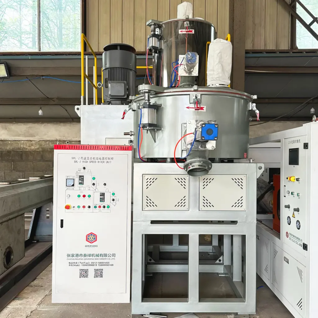 Industrial mixing unit with a control cabinet and metal vessel positioned on a factory floor with concrete walls and windows