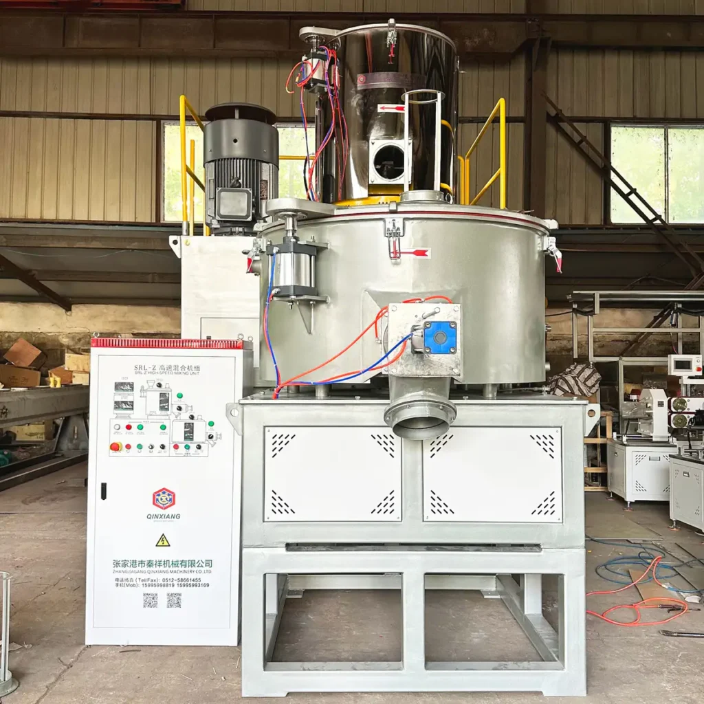 Industrial mixing vessel and control cabinet positioned in a factory workshop with visible structural beams and windows